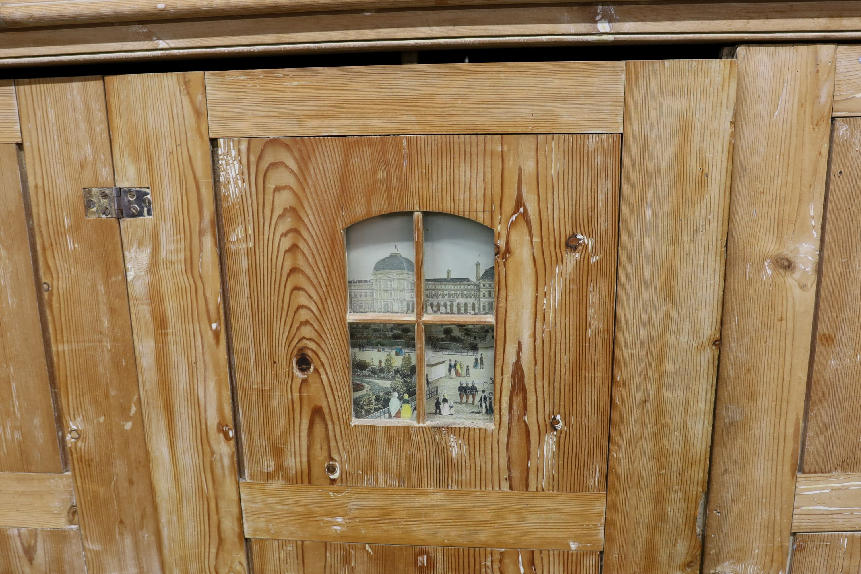 A 19th century stripped pine hall cupboard modelled as a dolls house the two door nine window facade enclosing a compartmented interior, width 182cm, depth 46cm, height 192cm